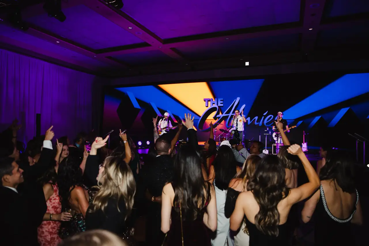 Alma Academy general session in a ballroom with a wide purple LED screen and a lighting truss overhead