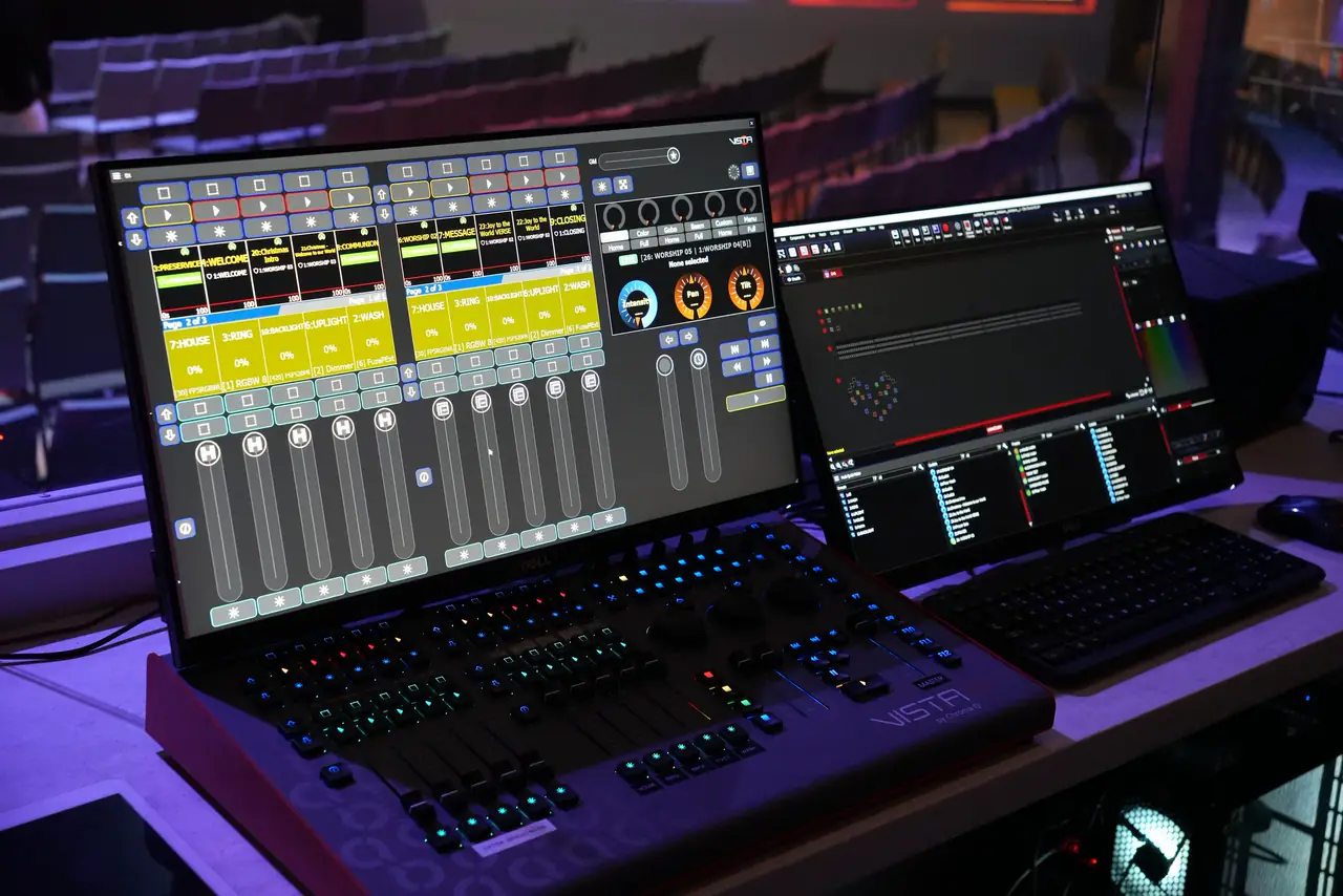 Lighting and audio control at City Church: console screens with faders and a laptop facing the room