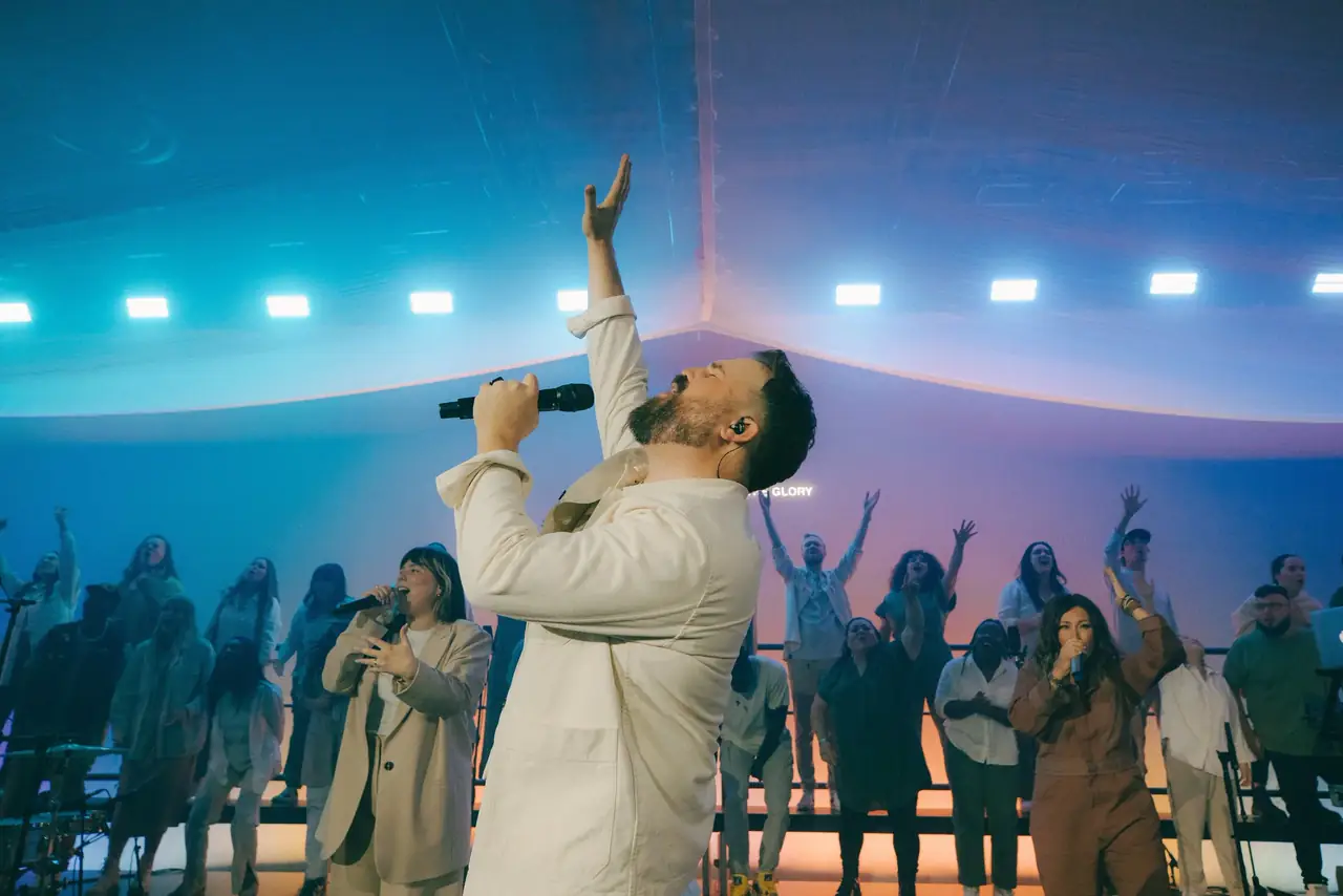Firm Foundation live recording: Cody Carnes in white under cyan light, the choir behind him