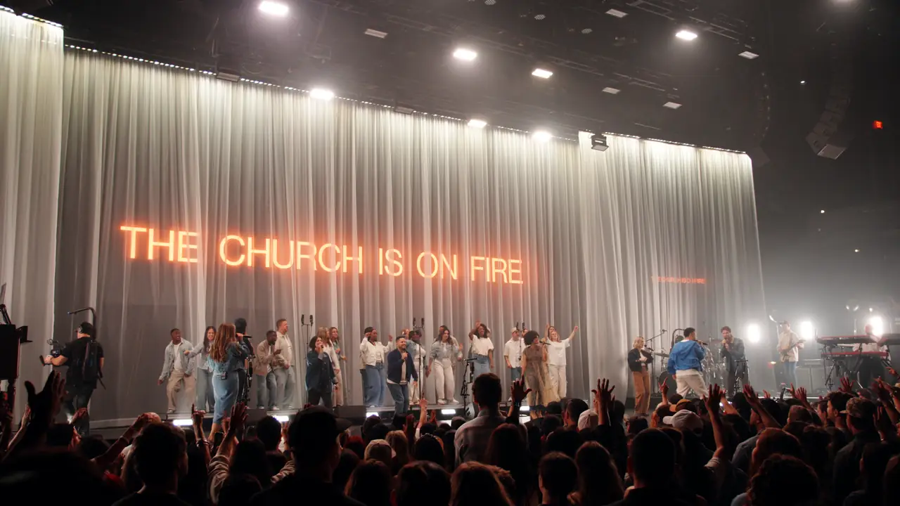 THE CHURCH IS ON FIRE in red letters across the full width of the drape, choir in white below