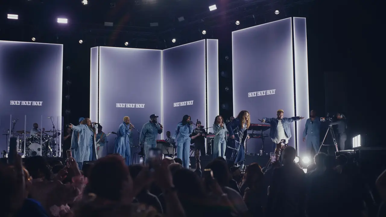 Cool-toned wide shot of the stage with lyrics on the panels and the band below