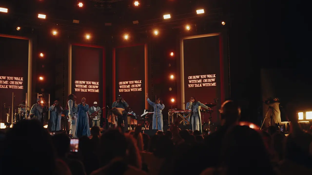 Red framed panels with lyrics behind the full band and singers
