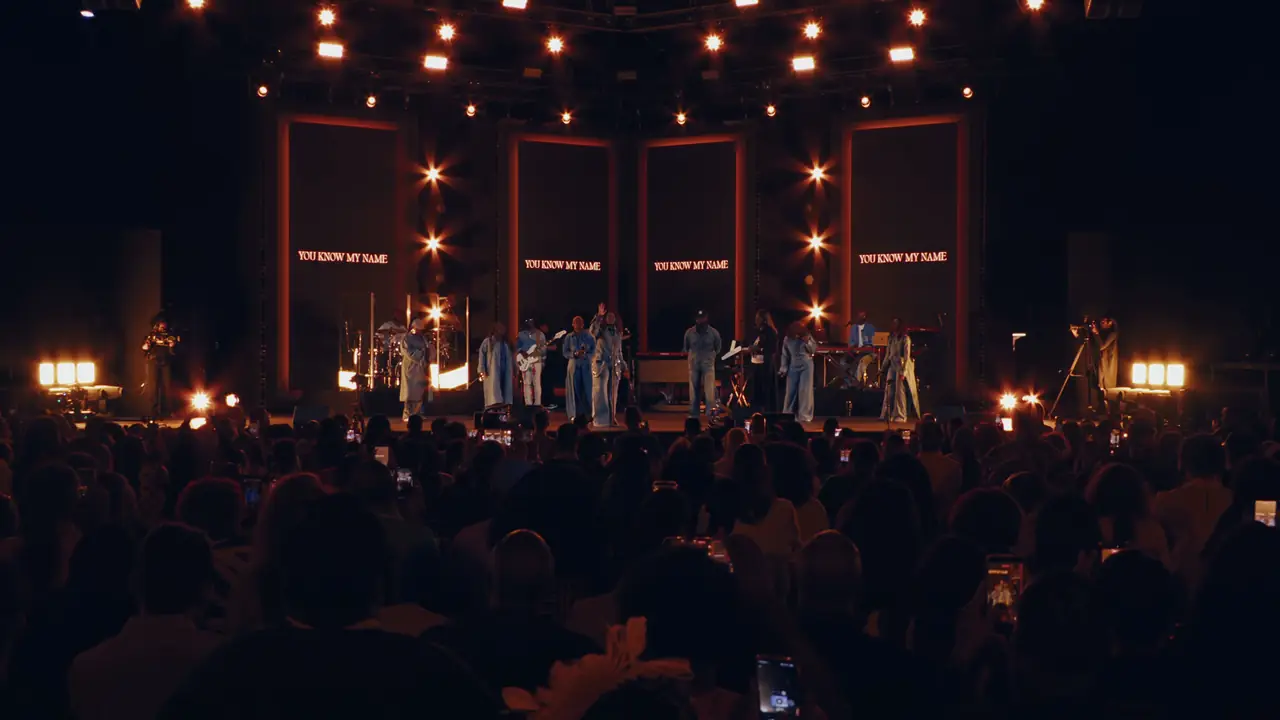 Wide stage view in red: lit frames across the set and a line of warm floor and overhead light
